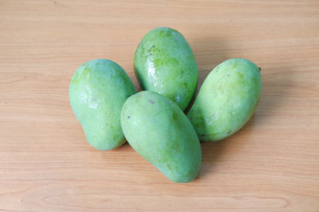 Mango fruit on wooden background, closeup of green mango fruitの写真素材
