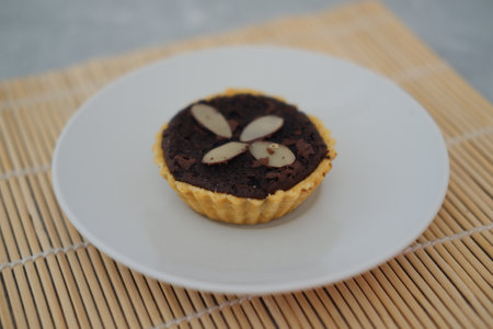 Chocolate tart with almond on white plate. Selective focus.の写真素材