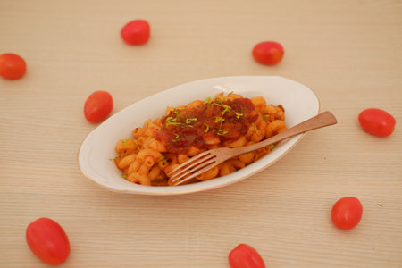 Macaroni with tomato sauce and onions on a white plate.の写真素材