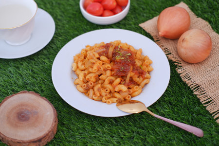 Macaroni with tomato sauce and onions on a white plate.の写真素材