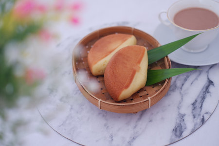 two pieces of a traditional soft and fluffy cake with a golden brown crust, served in a woven bamboo trayの写真素材
