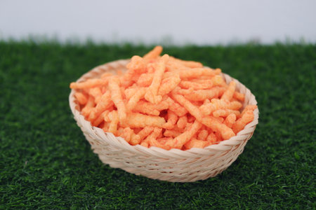 a woven basket filled with crunchy, bright orange snack sticksの写真素材