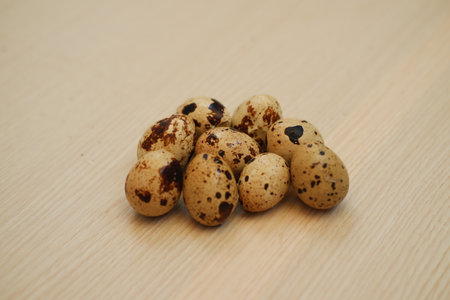 a cluster of quail eggs placed on a light wooden surfaceの写真素材