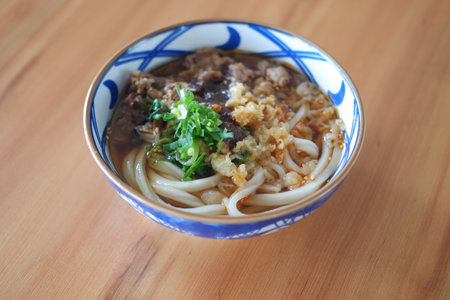 a bowl of savory Japanese udon noodles served in a flavorful brothの写真素材