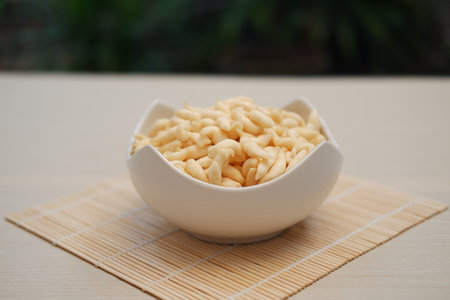 a white bowl filled with twisted, light-colored snacks that appear crispy and airyの写真素材