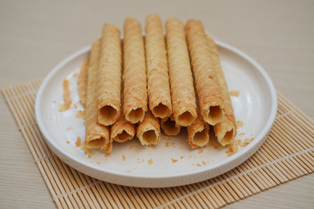 a white plate filled with rolled wafer sticks, neatly arranged in two layersの写真素材