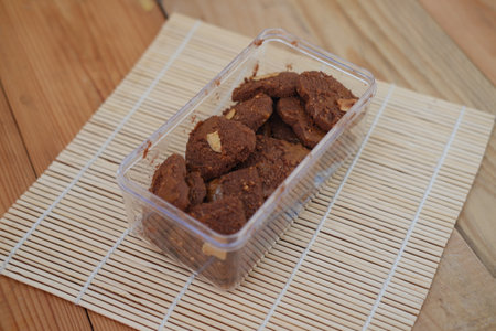 A clear plastic container holds a batch of rustic looking chocolate cookiesの写真素材
