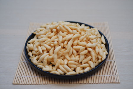 These snacks are placed neatly in a modern, petal-edged bowl that sits on a bamboo matの写真素材
