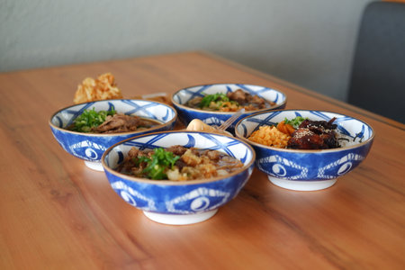a beautiful assortment of Japanese rice and noodle bowls arranged neatly on a wooden tableの写真素材