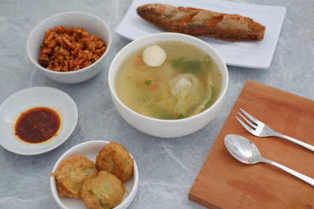 At the center is a bowl of clear soup containing vegetables, a fish ball, and possibly dumplings or cabbage.の写真素材