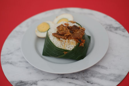 At the center is a portion of steamed white rice, neatly wrapped in a folded banana leaf, which adds a natural and rustic presentationの写真素材