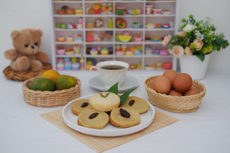 These soft, round cakes are garnished with raisins and pandan leaves, adding both flavor and visual appealの写真素材