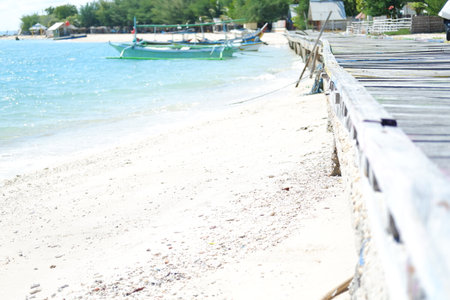 a peaceful beach scene with a wooden boardwalk running alongside a sandy shorelineの写真素材