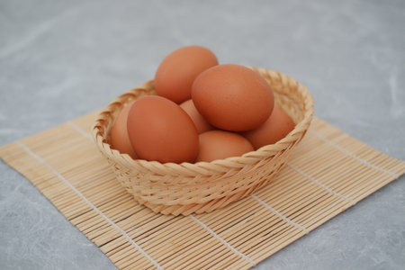 Eggs in a basket on a wooden matの写真素材