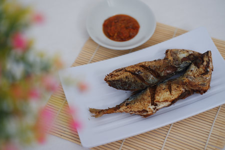 Delicious fried fish with spicy sauce on a white plateの写真素材