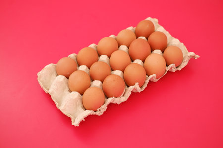 Fresh Brown Eggs in a Carton on a Pink Backgroundの写真素材