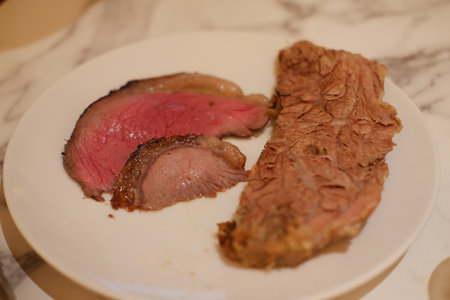 Sliced steak on a white plate, showing the texture and color.の写真素材