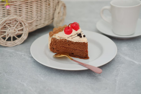 A delicious slice of chocolate cake with cherry topping on a white plate.