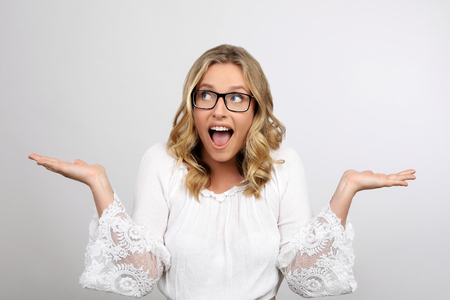 Blonde woman with glasses smiling and surprisedの写真素材