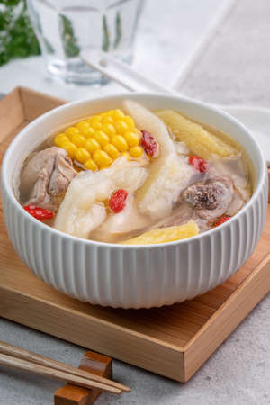 Taiwanese homemade delicious chicken soup food in a bowl with pineapple, bitter gourd and sweet corn on cement gray table background.の写真素材