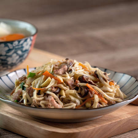 Pork meat julienne fried with water bamboo shred. Close up of delicious homemade food on wooden table background.の写真素材