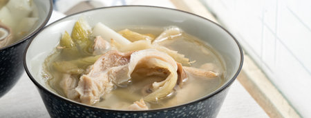 Pig stomach hog maw with pickled mustard green vegetable. Taiwanese traditional soup food in a bowl beside window table.の写真素材