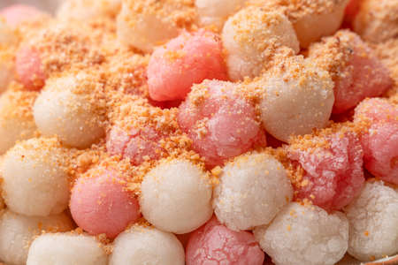 Close up of Deep-fried red and white tangyuan (tang yuan, glutinous rice dumpling balls) with peanut powder on gray table background for Winter solstice festival food.の写真素材