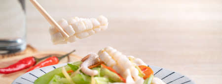 Stir-fried neritic squid with celery. Delicious homemade seafood with vegetable meal on wooden...