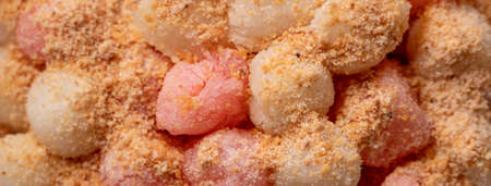 Top view of deep-fried red and white tangyuan (tang yuan, glutinous rice dumpling balls) with peanut powder on wooden table background for Winter solstice festival food.の写真素材