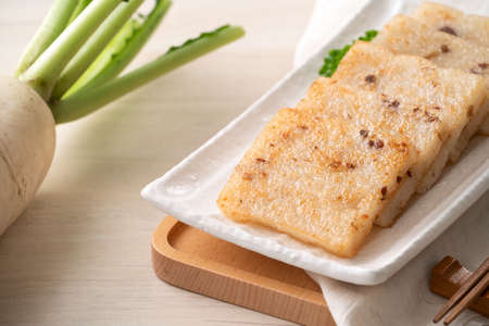 Close up of delicious Chinese radish cake in a plate on wooden table background.の写真素材