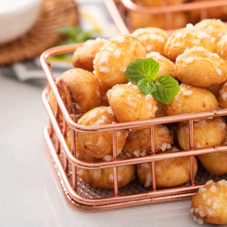 Delicious French Chouquette Choux Pastry dessert Pearl Sugar Puff in a basket on white marble background with a cup of milk tea, afternoon tea concept.の写真素材