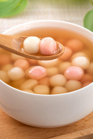 Little red and white tangyuan (tang yuan, glutinous rice dumpling balls) with sweet syrup soup in a bowl for Winter solstice festival food.の素材 [FY310195658085]