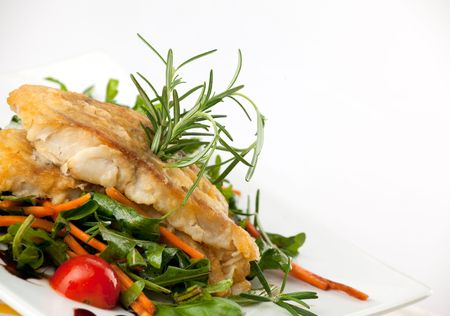 pan seared fillet of white fish and vegetables on white background の写真素材