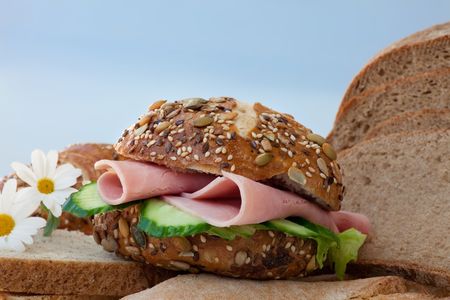Sliced ham sandwich with lettuce and cucumber on a seeds bun.の写真素材