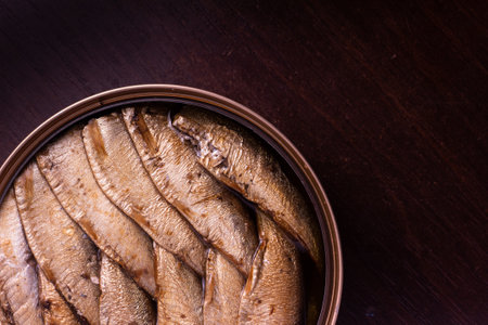 close-up photo of canned fish - sprats in oil - on a dark wooden background