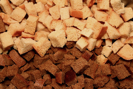 a lot of ruddy fried square croutons of white and black bread randomly scattered in a pile - close-up top viewの写真素材