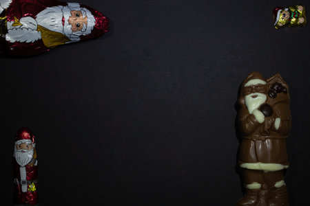 Three chocolate Santas - big and small and New Year's Santa Claus made of dark and white chocolate with a festive teddy bearの写真素材