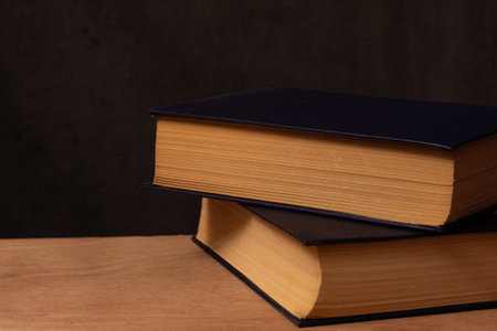 photo still life of two books on a wooden board on a dark background with empty space