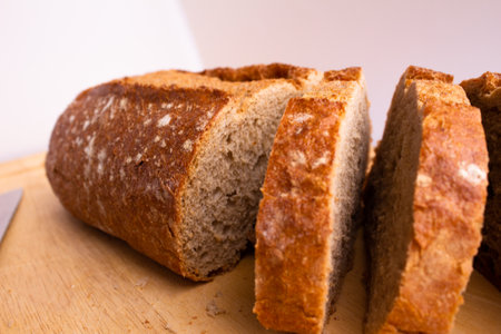 close-up of bread which is sliced on a wooden cutting board - on a white background