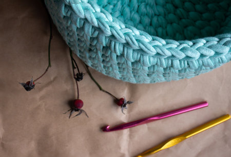 Basket made of cotton cord on a background of light brown wrapping paper and crochet hooks - top viewの写真素材