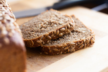 Two slices of wholesome whole grain bread, rich in seeds, displayed on a cutting board ready for...