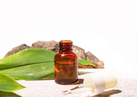 Natural cosmetology background. A glass dropper bottle with a pippette on eco materials like cement,...