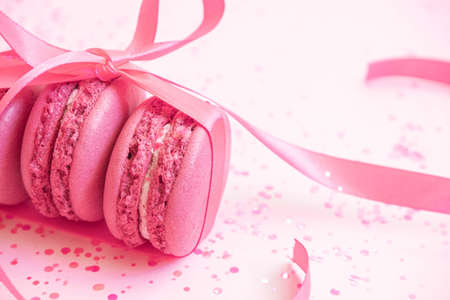 Pink macaroons wrapped in ribbon on glitter background. Pasrty party. Pastel colorの写真素材