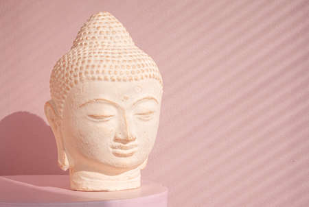 White Buddha bust on pastel pink background decorated with shades. Boho asian style. Relax mood....