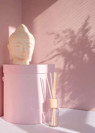 White Buddha bust on pastel pink background decorated with shades. Boho asian style. Relax mood....