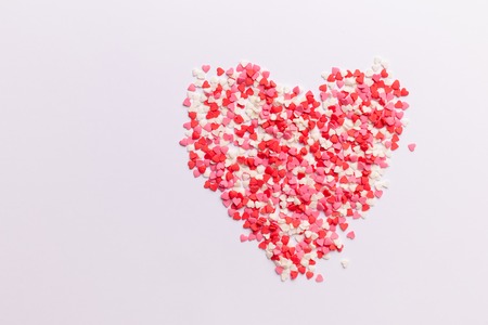 Red, pink and white heart shaped sweets in the shape of a heart scattered on white background. space for text. flat lay. valentine conceptの写真素材