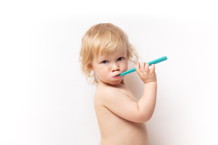 little cute curly baby smiles and cleans teeth on white backgroundの写真素材