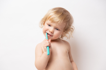 little cute curly baby smiles and cleans teeth on white backgroundの写真素材