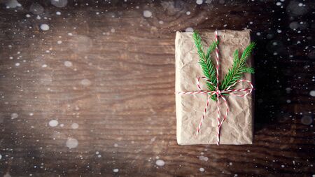 Top view of colorful decorated craft gift box on a retro wooden table with pineand snow. border...