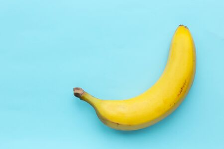 juicy yellow not perfect banana on a blue background.の写真素材